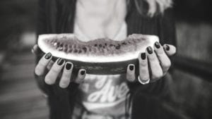A monochrome photo of a woman holding a slice of watermelon, embodying the idea of healthiness.