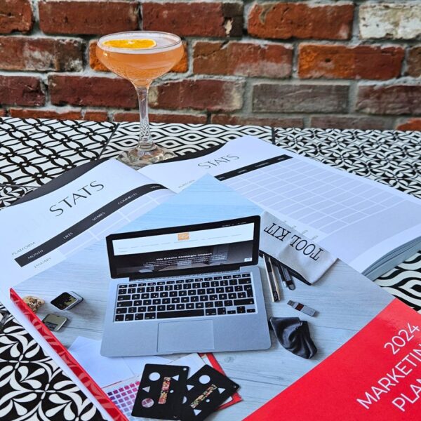 The Marketing Planner - 2024 Edition sits on a table next to a cocktail, showcasing marketing strategies.