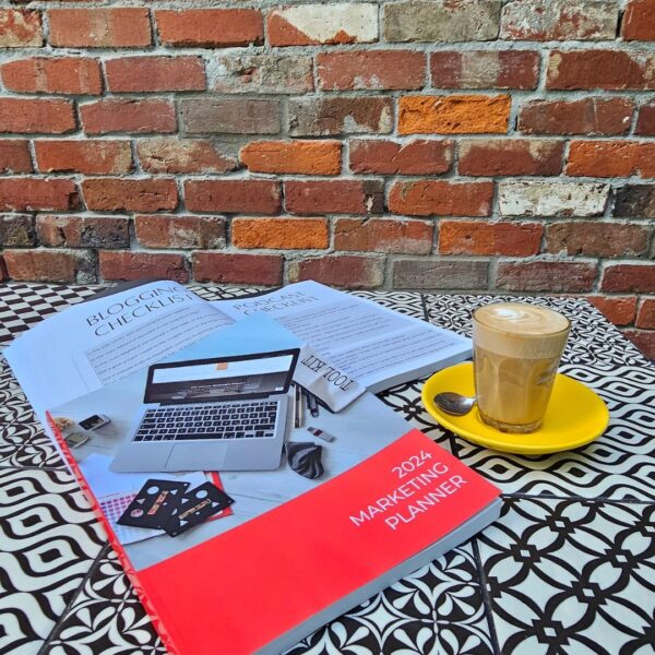 The Marketing Planner - 2024 Edition on a table in front of a brick wall, representing marketing.