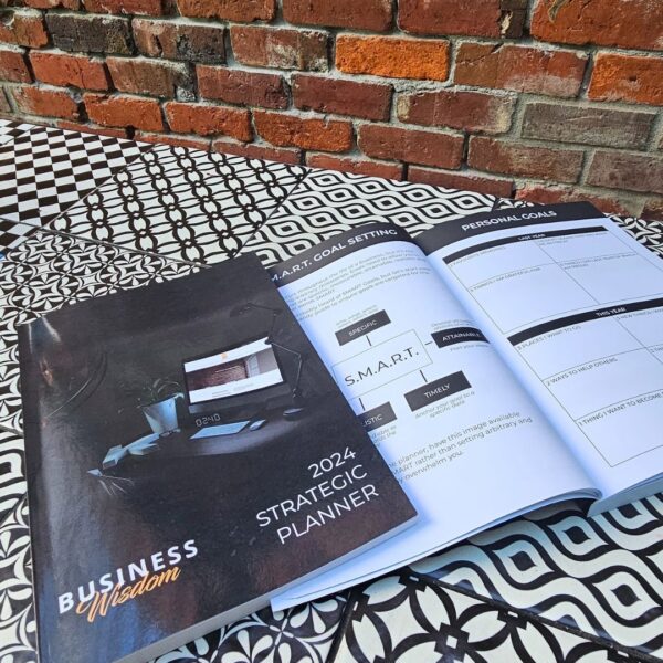 The Strategic Planner - 2024 Edition on a table next to a brick wall.