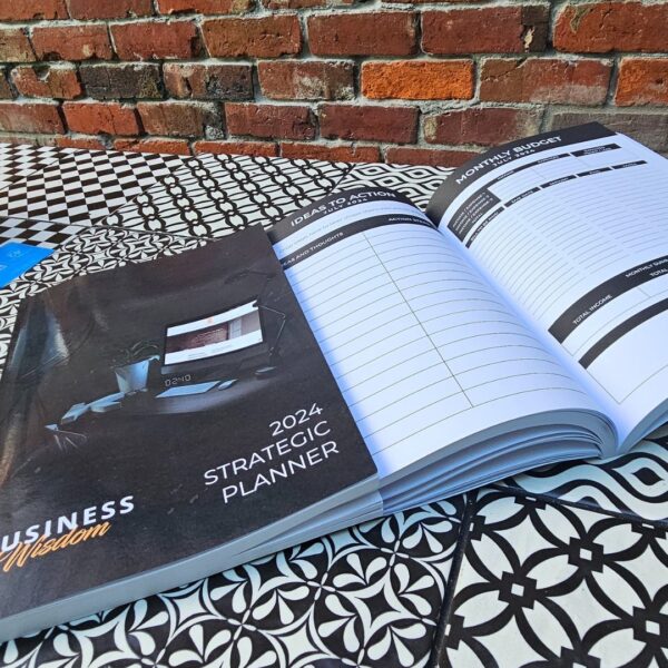 The Strategic Planner - 2024 Edition book on a table next to a brick wall.