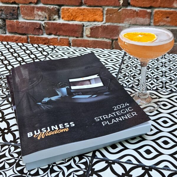 A cocktail and The Strategic Planner - 2024 Edition strategically placed on a coffee table.