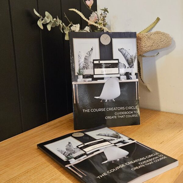 The Course Creation Guidebook To Create That Course sits on a table next to a vase of flowers.