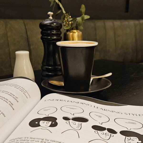 An open book on a table with a cup of coffee, serving as The Course Creation Guidebook To Create That Course.