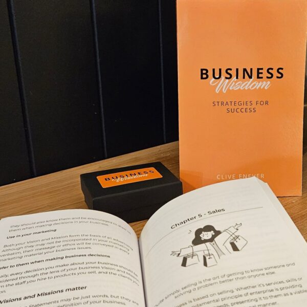 A Business Wisdom: Strategies for Success book next to an orange book on a table.