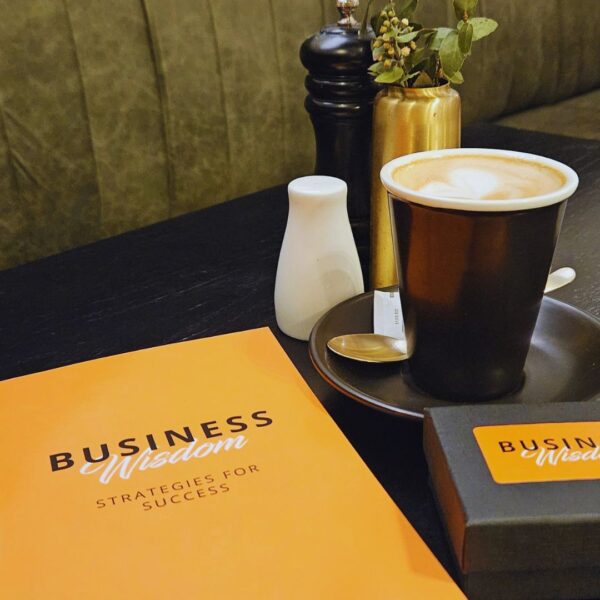 A cup of coffee sits on a table next to a Business Wisdom: Strategies for Success representing wisdom.