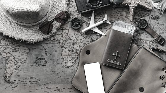A suitcase, hat, sunglasses and phone on a map.