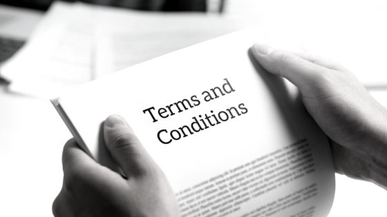 A person holding up a document that says terms and conditions.